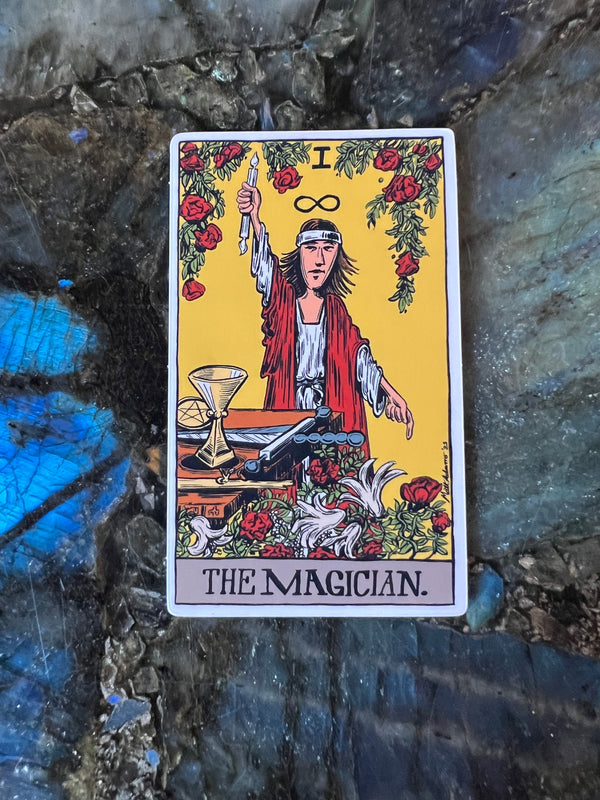 A stylized rendition of The Magician from Rider Waite Smith tarot sitting on a labradorite crystal background. The Magician famously has all four elements present on his altar.