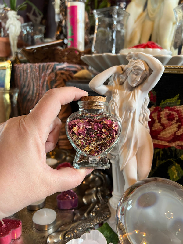 A heart holding a bottle filled with rose petals