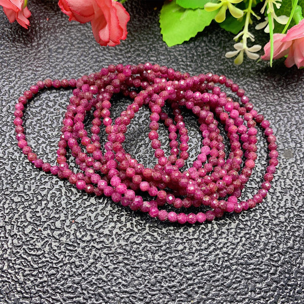 A pile of bracelets. They are all stretch bracelets made from petite ruby beads, cut with facets so they sparkle in the light