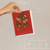 Red card with a strawberry design held by a hand against a beige background