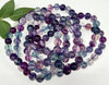 Multicolored beaded bracelets on a white background with a green leaf