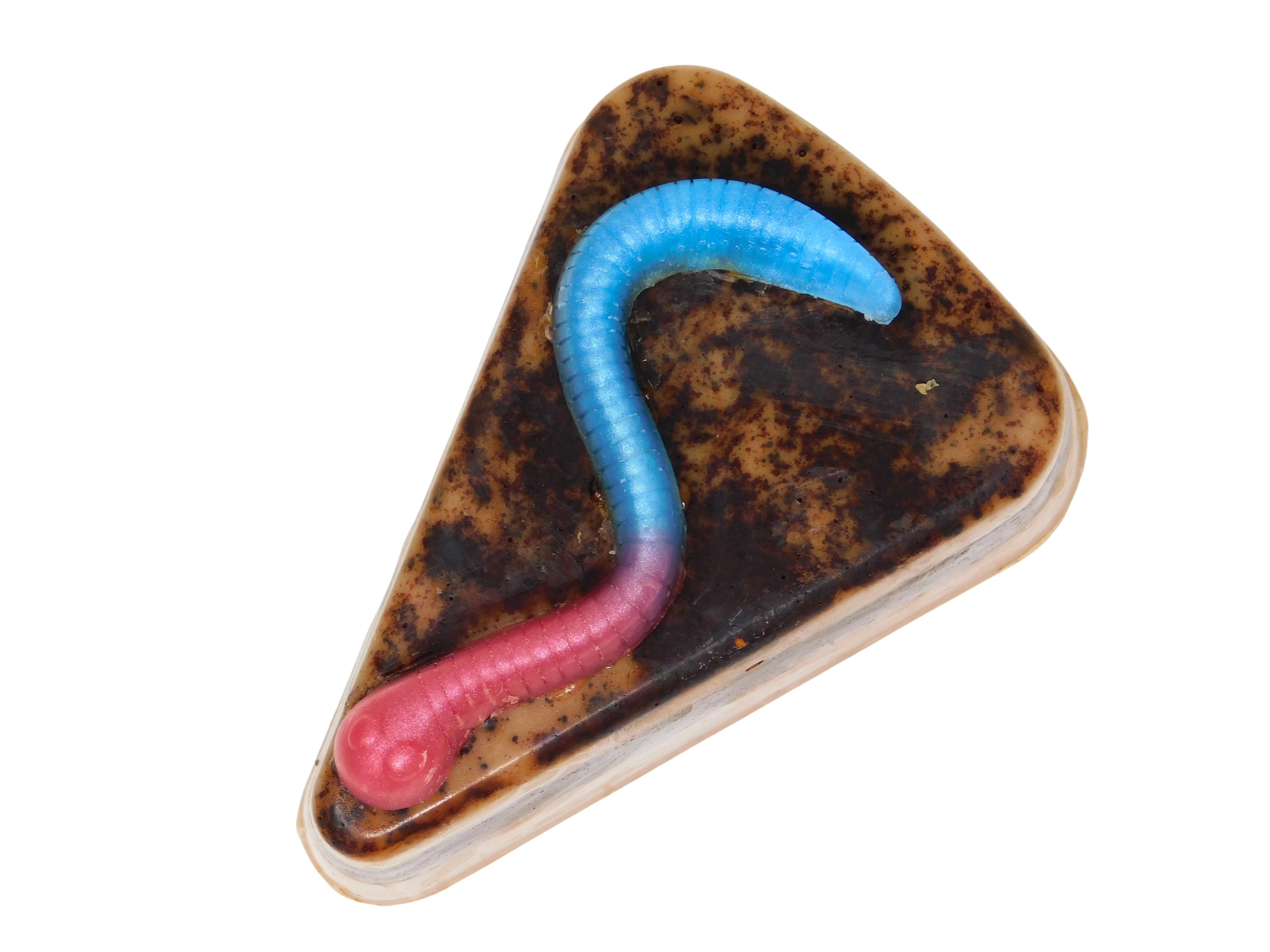 Graveyard Dirt Cake Soap - triangular slice-shaped soap with layered chocolate and caramel tones, real cocoa topping, and a pink and blue gummy worm embed on top, on a white background