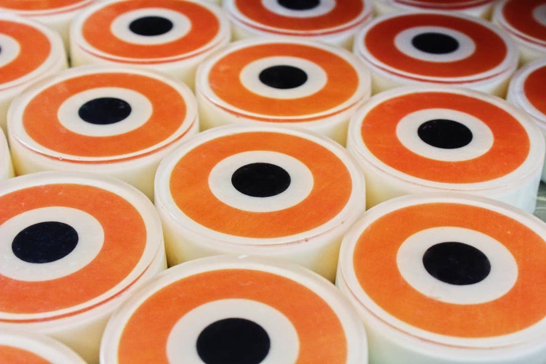 Rows of Somebody's Watching Me Evil Eye Soaps showing the orange and black concentric circle pattern from above, lined up fresh from production