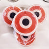 Three Somebody's Watching Me Evil Eye Soaps wrapped in cellophane showing the red and white evil eye design, stacked on a white surface