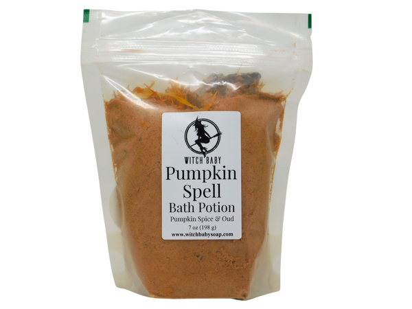 Pumpkin Spell Bath Potion in a clear biodegradable standup bag with Witch Baby label showing Pumpkin Spice and Oud scent, filled with warm orange pumpkin and clay powder, 7 oz