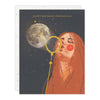 Greeting card with illustration of a woman blowing a bubble towards a moon, text 'Happy Birthday Moonchild' on a dark background.