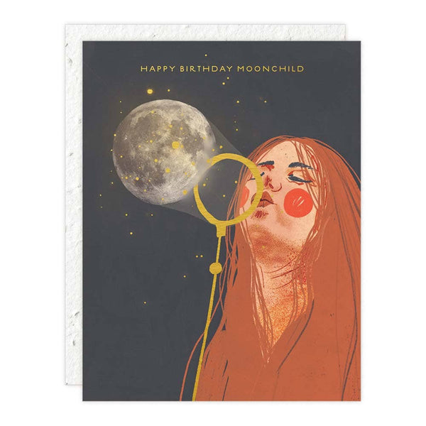 Greeting card with illustration of a woman blowing a bubble towards a moon, text 'Happy Birthday Moonchild' on a dark background.