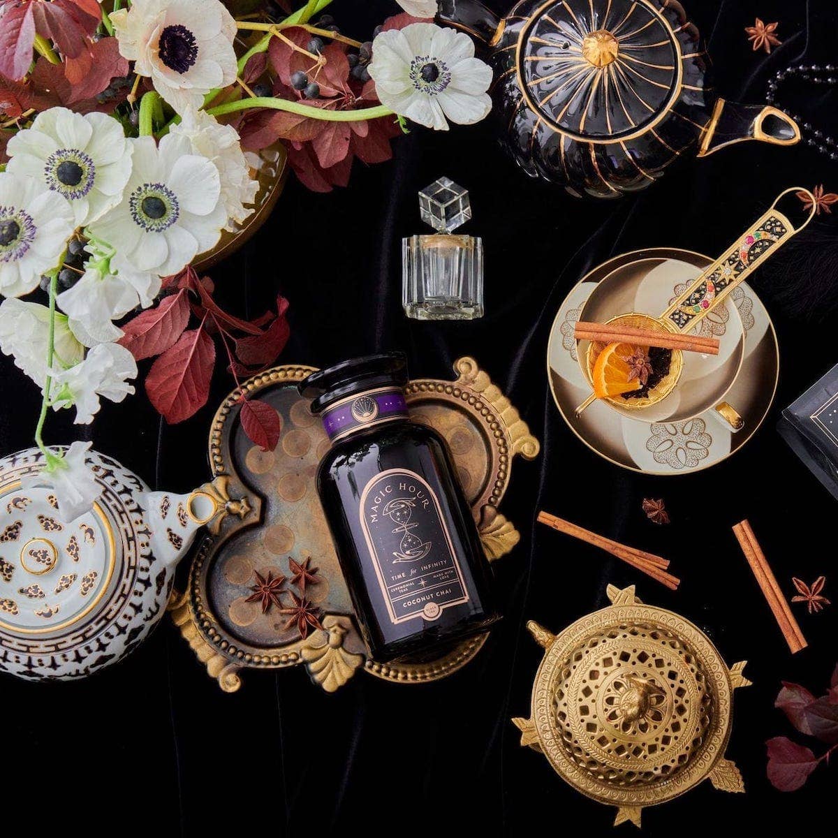 A tasteful arrangement of tea serving accessories, flowers, and a luxe bottle of Coconut Chai