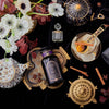 A tasteful arrangement of tea serving accessories, flowers, and a luxe bottle of Coconut Chai