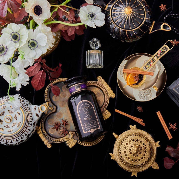 A tasteful arrangement of tea serving accessories, flowers, and a luxe bottle of Coconut Chai