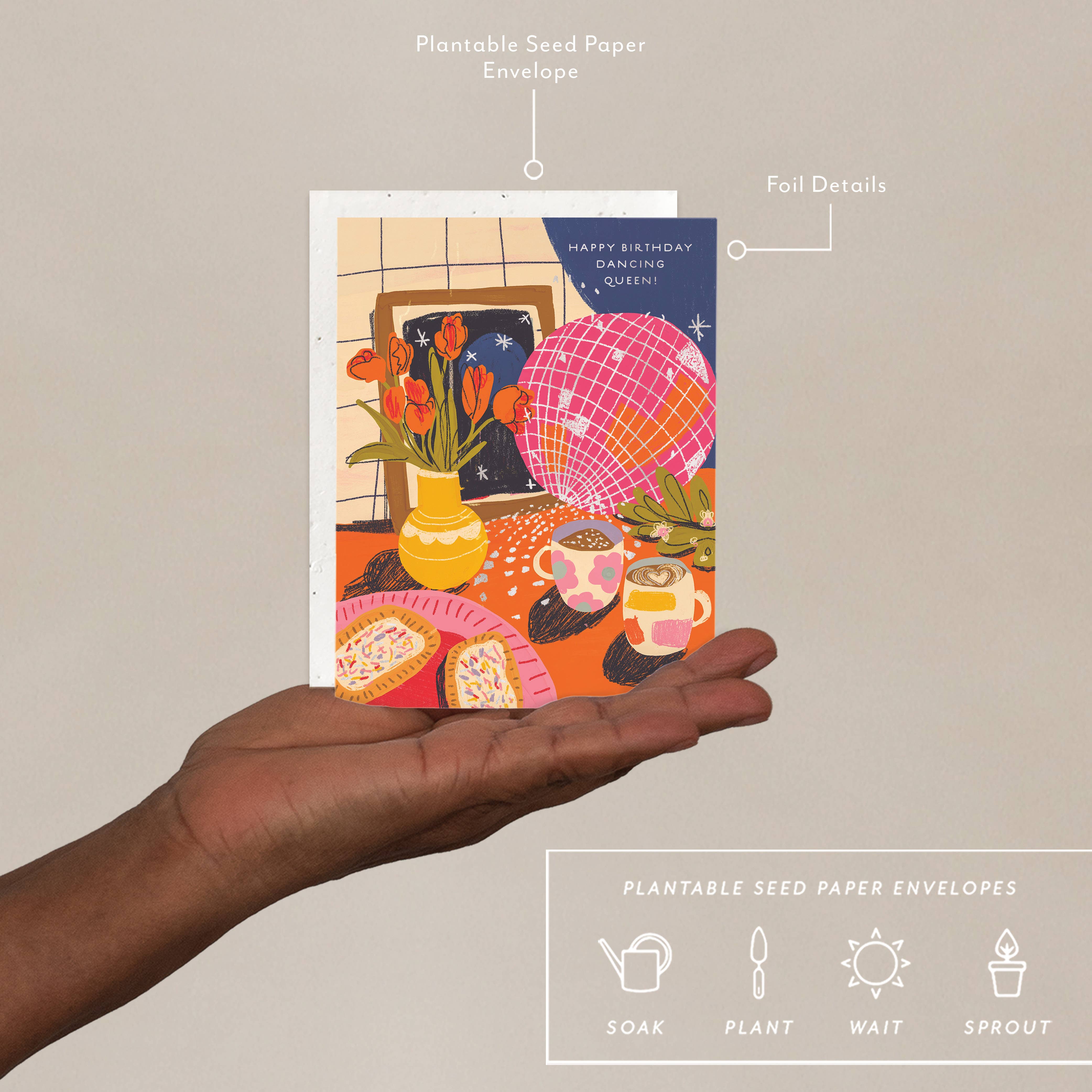 Hand holding a colorful greeting card with plantable seed paper envelopes feature.