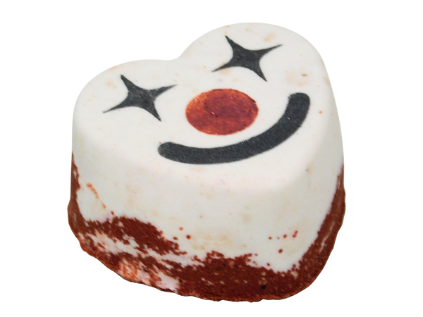 Funhouse Bath Fizz angled view showing the heart shape with red glittered base, white top, and clown face with sparkle eyes, red nose, and black smile