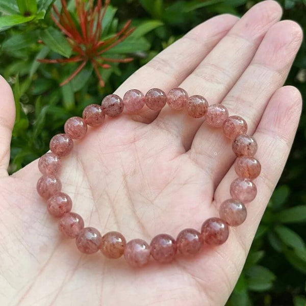 One strawberry quartz bracelet sitting in a hand