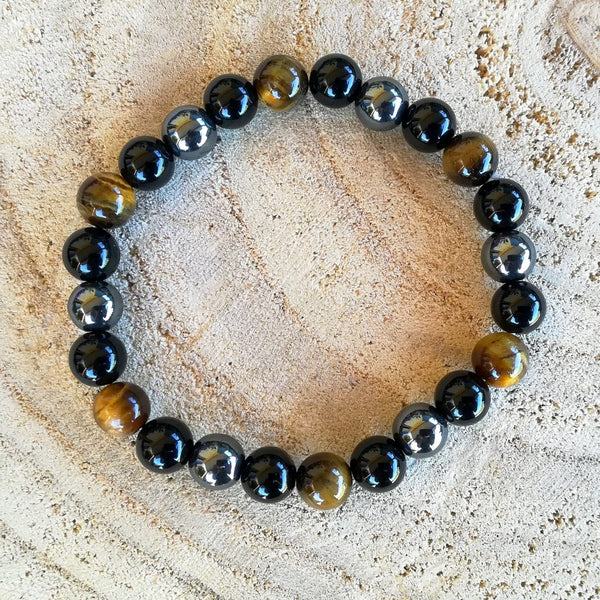 A beaded stretch bracelet made of glossy round beads, featuring alternating black onyx beads, dark gray hematite beads, and tiger's eye beads with brown and gold banding