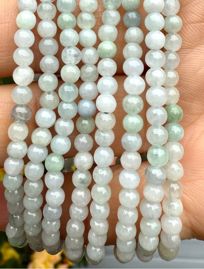 Three strands of light green jade beads held in a hand.