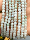 Three strands of light green jade beads held in a hand.