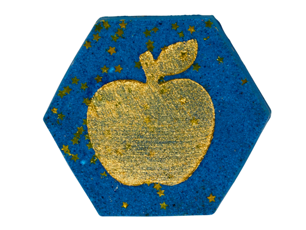 Opal Apple Bath Fizz - deep blue hexagon bath fizz with a gold metallic apple embossed on top and gold star confetti scattered across the surface, on a white background