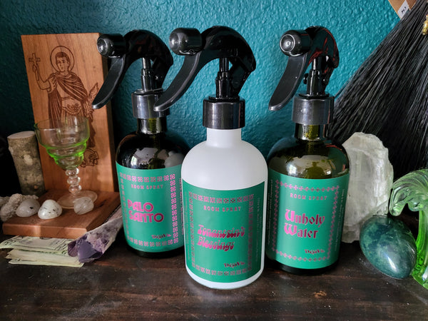 Three bottles with green labels on a wooden surface against a teal wall.