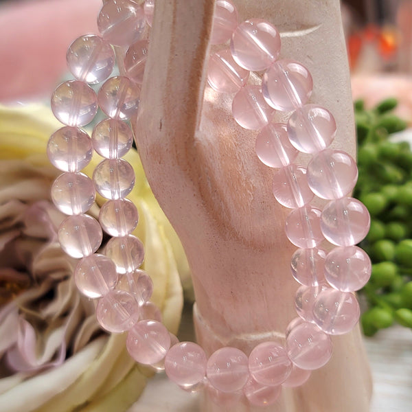 Pale pink star rose quartz bracelets held by a wooden hand